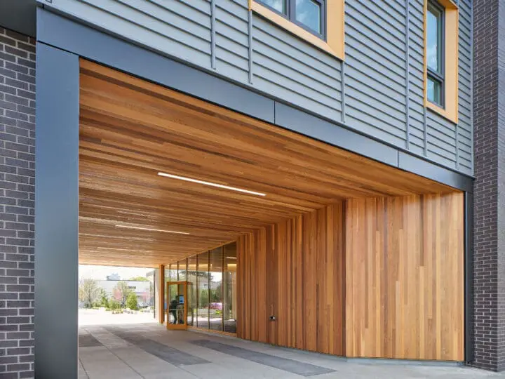A person opens the door in the warm-toned, wooden-clad breezeway at 72Foster.